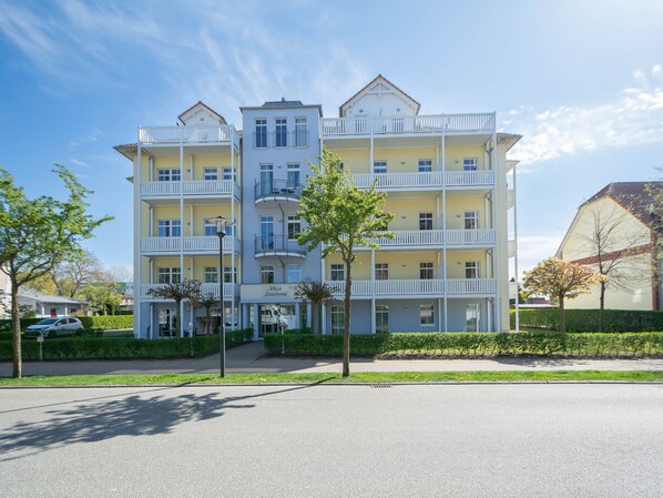 Un hôtel à plusieurs étages, doté de balcons, d’une entrée bien visible et d’une pelouse bien entretenue.
