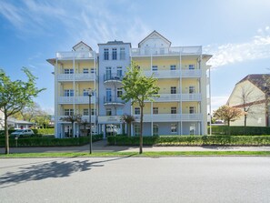 A multi-story hotel with balconies, a visible entrance, and a well-maintained lawn.