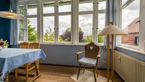 En matplats med ett bord och stolar, stora fönster och ett element.
