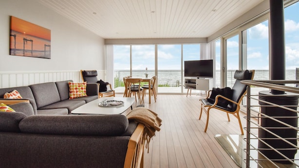 A modern living room with a sofa, coffee table, TV, and a balcony overlooking the sea. - Awesome home in Nyborg with WiFi (Nyborg)