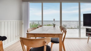 A wooden table with six chairs in a room with large windows overlooking a body of water. - Awesome home in Nyborg with WiFi (Nyborg)