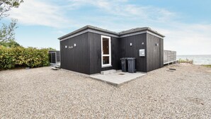 A two-story building with a dark exterior, a white door, and a small porch area. - Awesome home in Nyborg with WiFi (Nyborg)