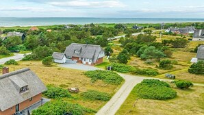 A coastal village with houses, a road, and a beach in the background.