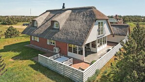 A house with a sloped roof, a balcony, and a fenced patio area.