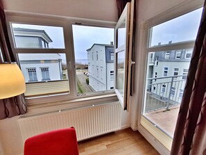 A room with a large window, a radiator, and a red chair.