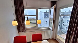 A room with a table, chairs, a radiator, and a window with curtains. - Apartment Perlmuschel (A) - Villa Ahlbeck House 2 (Heringsdorf)