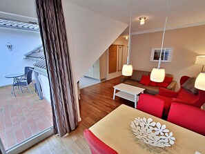 Un salon moderne avec un canapé, une table basse et une table à manger. Il y a un balcon avec une table et des chaises à l'extérieur.