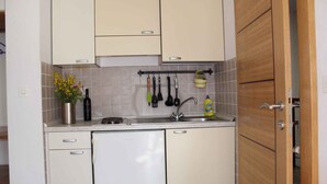 A compact kitchen with white cabinets, a stainless steel sink, and a dish drying rack.