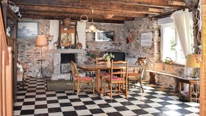 A rustic room with a checkered floor, wooden furniture, a stone wall, and a fireplace. - Lovely home in Le Faouet with kitchen (Le Faouet)