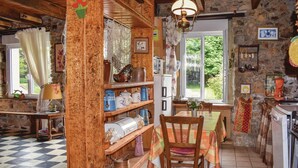 A rustic kitchen with wooden shelves, a dining table, and a view of greenery outside. - Lovely home in Le Faouet with kitchen (Le Faouet)
