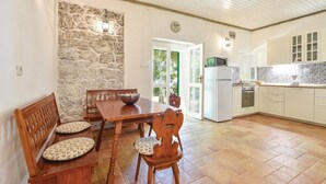 A dining area with a stone wall, wooden table, and chairs.