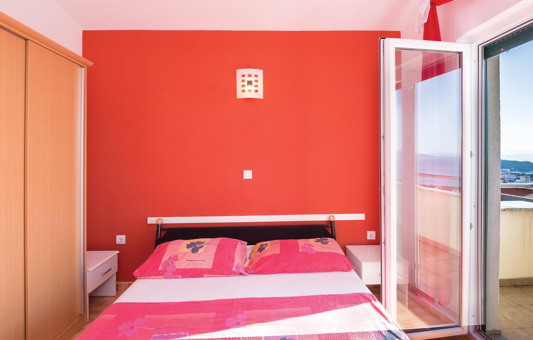 Un dormitorio con cama, armario y puerta corrediza de vidrio a un balcón.