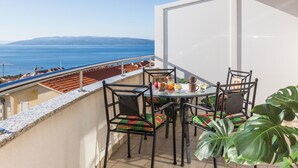 A balcony with a table and chairs, overlooking a coastal view with buildings and the sea. - 2 bedroom beach front apartment in Makarska (Makarska)