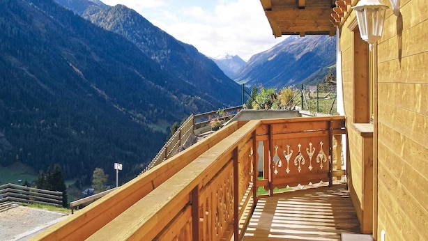 Un balcon en bois offrant une vue sur un paysage montagneux.