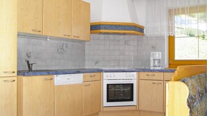 Une cuisine de taille réduite, avec des meubles en bois, une cuisinière blanche et une machine à café.