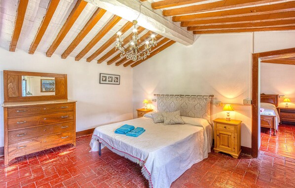 A bedroom with a bed, wooden dresser, and a chandelier.