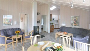 Een moderne woonkamer met twee banken, een eettafel en een keuken op de achtergrond.