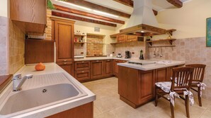 A kitchen with wooden cabinets, a large island with a sink, and a dining area with chairs. - Pet friendly home in Visnjan (Visnjan)