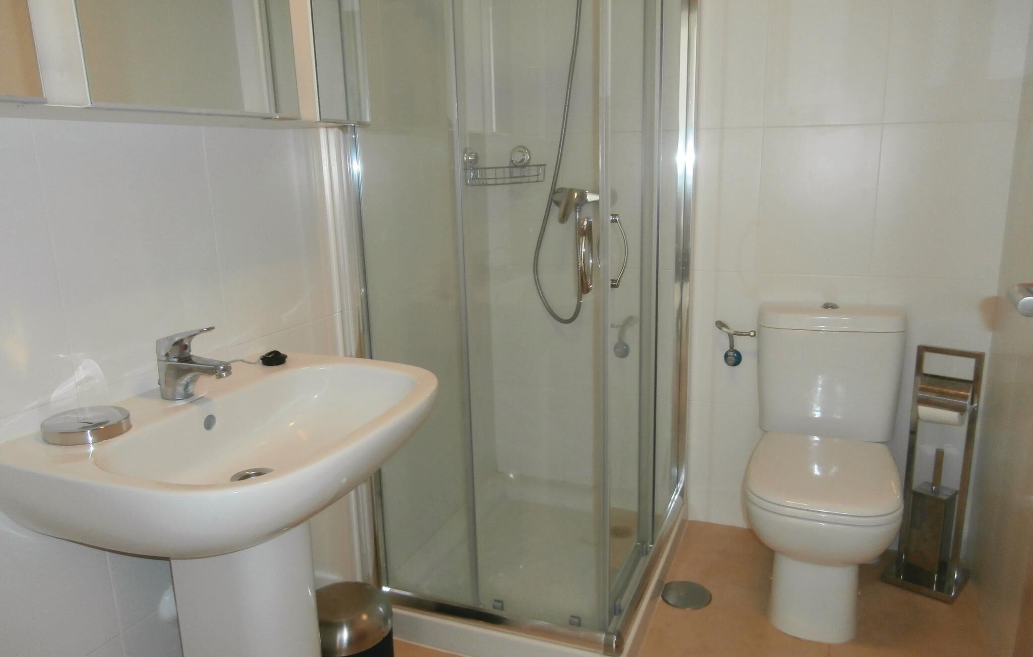 A bathroom with a glass-enclosed shower, a sink, and a toilet.
