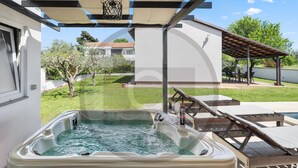 A hot tub with lounge chairs, a pergola, and a view of a residential area. - Beach front home in Valbandon (Valbandon)