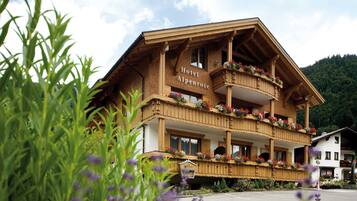 A hotel with a wooden facade, balconies with flower boxes, and a sign reading 'Hotel Alpenrose.'