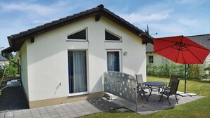 Una piccola casa a un piano con tetto spiovente e un ombrello rosso.
