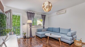 Un salon moderne avec un canapé bleu, une petite table blanche et un luminaire suspendu.