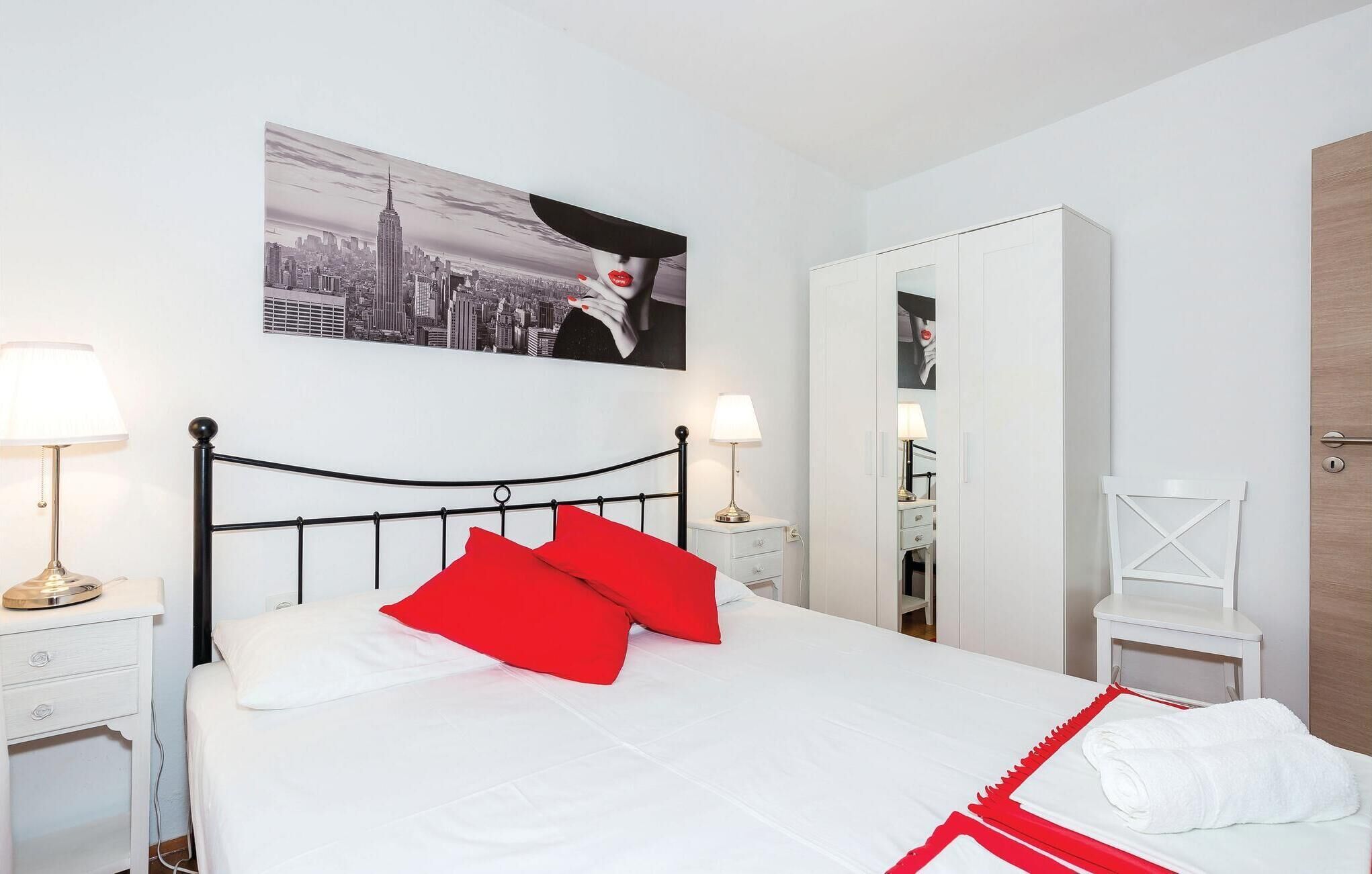 A hotel room with a bed, two bedside lamps, a nightstand, a mirror, and a wardrobe.
