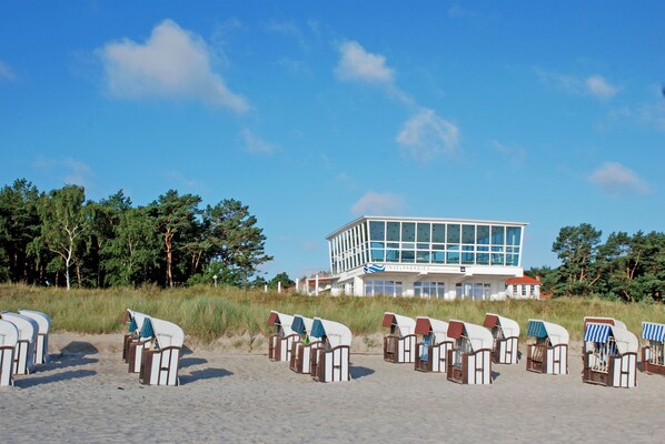 Un edificio moderno frente a la playa, con filas de sillas y vista despejada al océano.