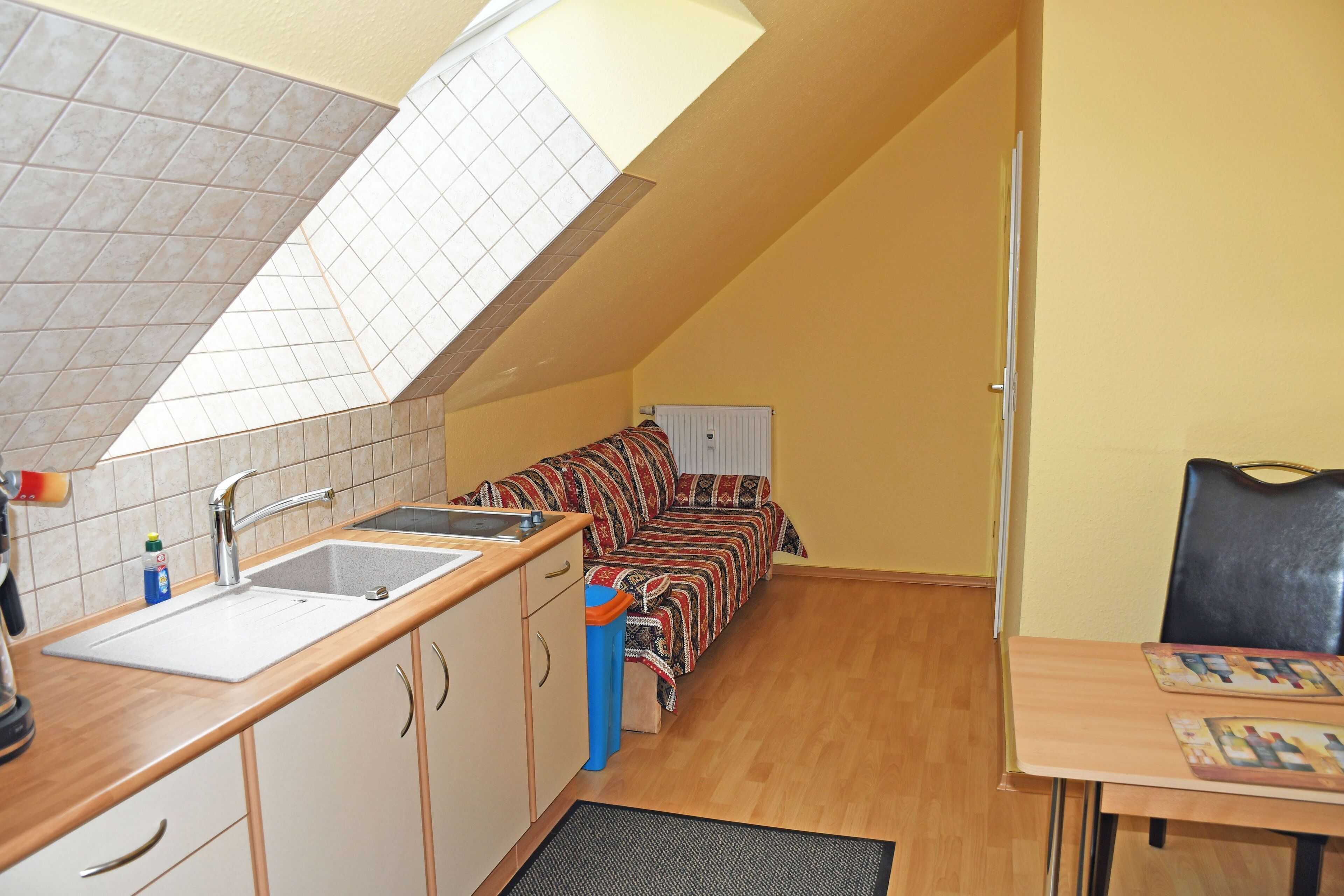 A compact kitchen with a sink, cabinets, and a window above the countertop.
