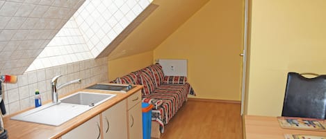 A compact kitchen with a sink, cabinets, and a window above the countertop.