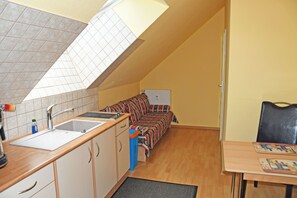 A compact kitchen with a sink, cabinets, and a window above the countertop.
