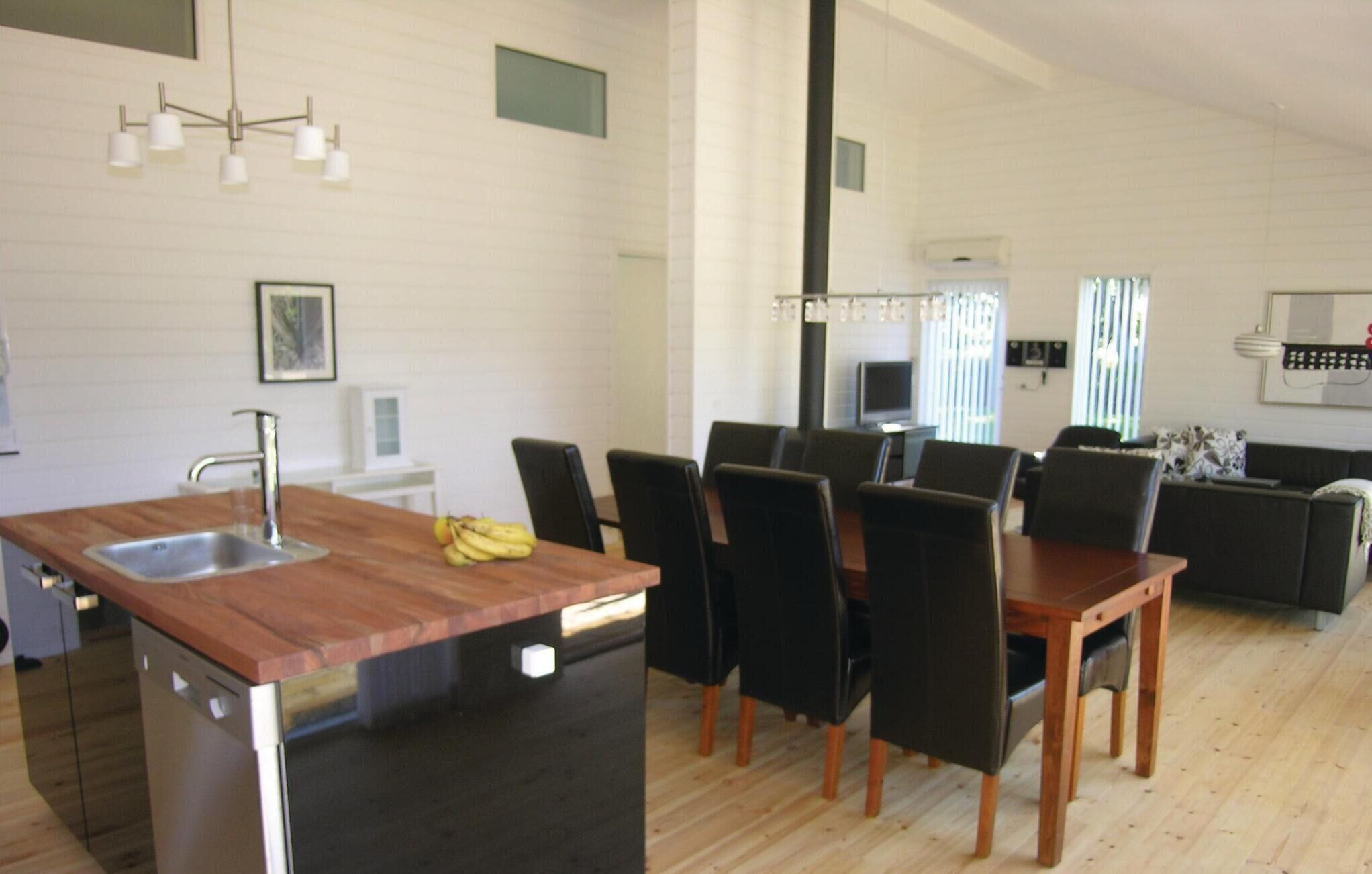 A modern kitchen with a wooden countertop, black chairs, and a dining table.