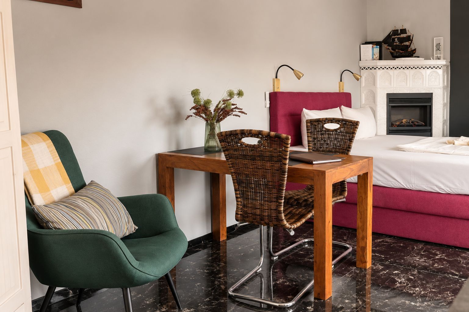 Ein modernes Schlafzimmer mit einem Bett, einem Tisch mit Stühlen, einem Kamin und einem grünen Sessel.