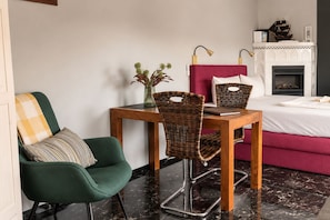 Un dormitorio moderno con cama, una mesa con sillas, una chimenea y un sillón verde.