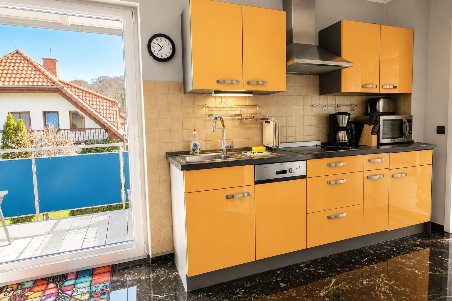 A modern kitchen with yellow cabinets, a stainless steel sink, and a microwave.