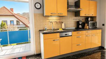 A modern kitchen with yellow cabinets, a stainless steel sink, and a microwave.