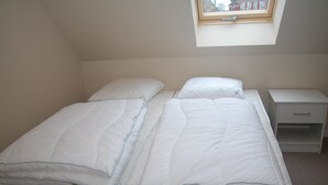 A small, single-bed room with a skylight above the bed, a bedside table with a drawer, and a plain wall. - 2 bedroom stunning apartment in Gudhjem (Gudhjem)