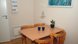 A dining area with a wooden table and four chairs, a potted plant, and two blue cups. - 2 bedroom stunning apartment in Gudhjem (Gudhjem)