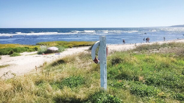 A beach with a lifeguard tower, sandy shore, and ocean view. - 2 bedroom stunning apartment in Gudhjem (Gudhjem)