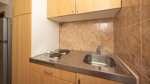 Een keuken met houten kastjes, een roestvrijstalen spoelbak en een gasfornuis.