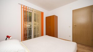 Een slaapkamer met een bed, een kledingkast en een deur.