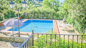 Ein Pool mit einer Steindeck, umgeben von üppiger Vegetation und einem Bergpanorama.