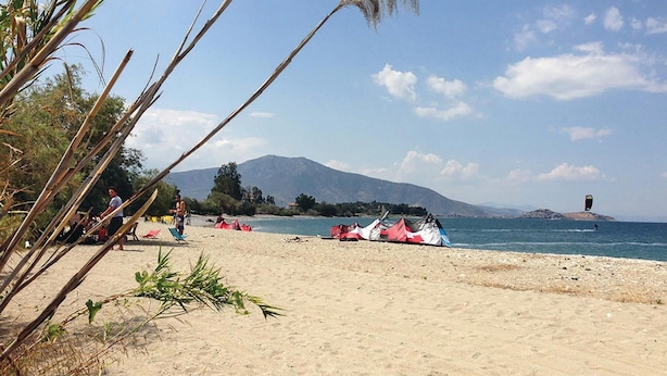 Una playa con tiendas de campaña y una montaña al fondo.