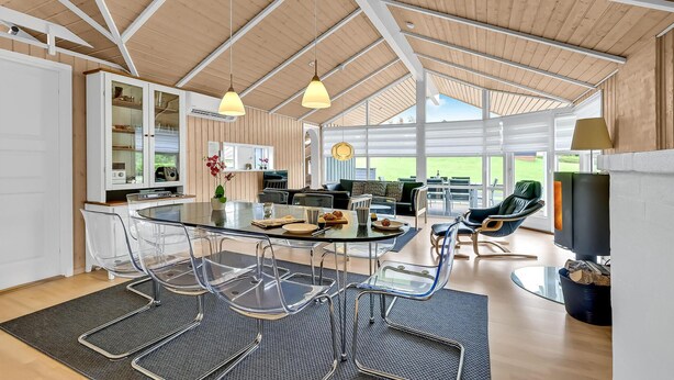 Una cocina amplia con electrodomésticos modernos, un comedor con mesa y sillas de vidrio, y una sala de estar acogedora con sofá y televisor.