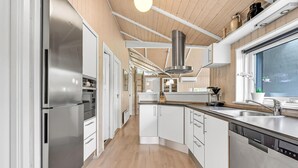 Una cocina moderna con electrodomésticos de acero inoxidable, armarios blancos y techo de madera.