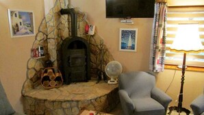 A living room with a stone fireplace, a television mounted on the wall, and a lamp. - Holiday home with terrace and barbecue (Balatonboglár)