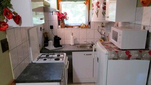 A compact kitchen with a gas stove, a microwave, a sink, and a small refrigerator. - Holiday home with terrace and barbecue (Balatonboglár)