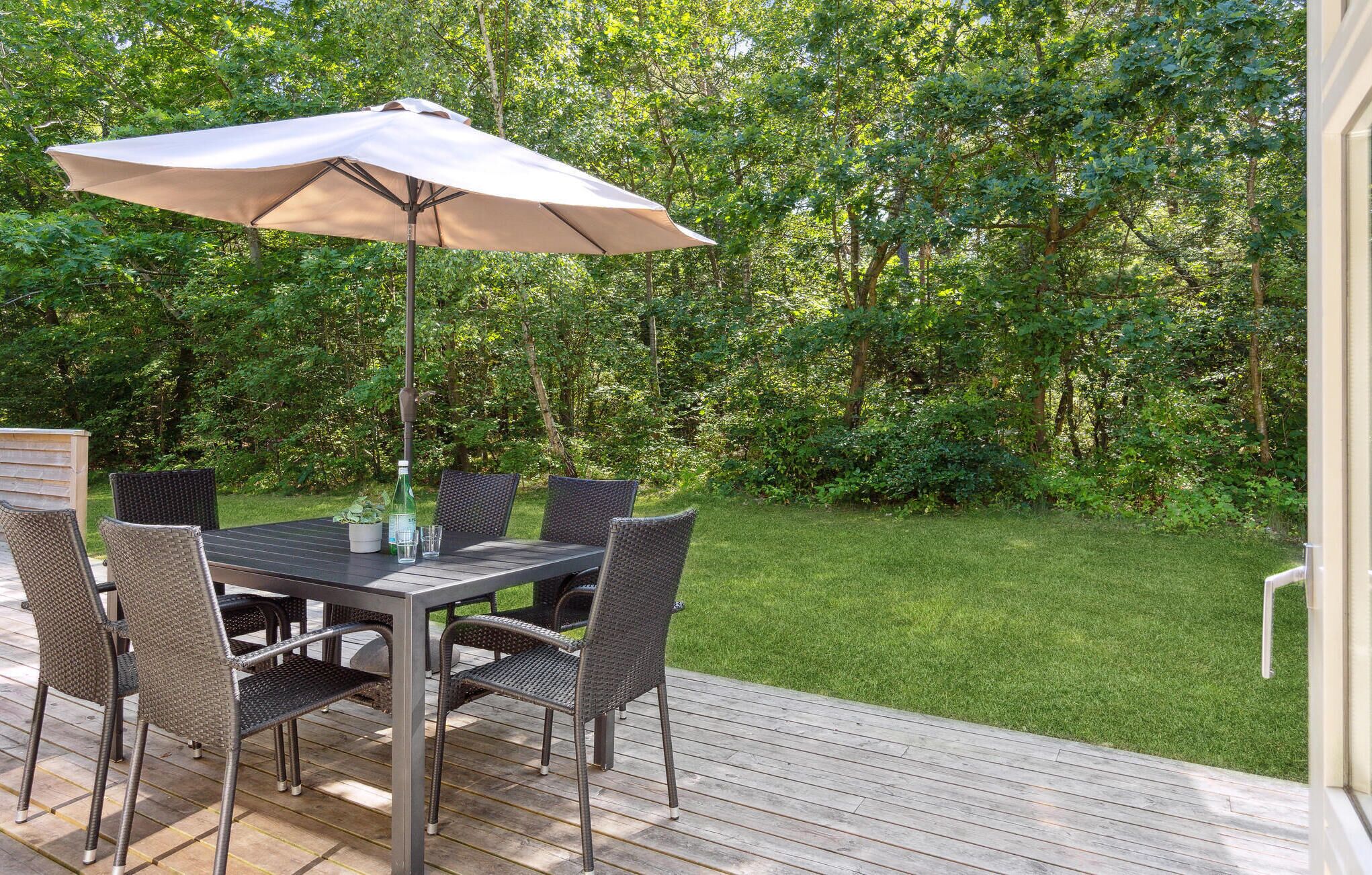 A deck with a table and chairs, surrounded by a lush garden.
