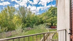 A balcony with a view of a garden and a stone wall. - Stunning home in Malinska (Malinska)